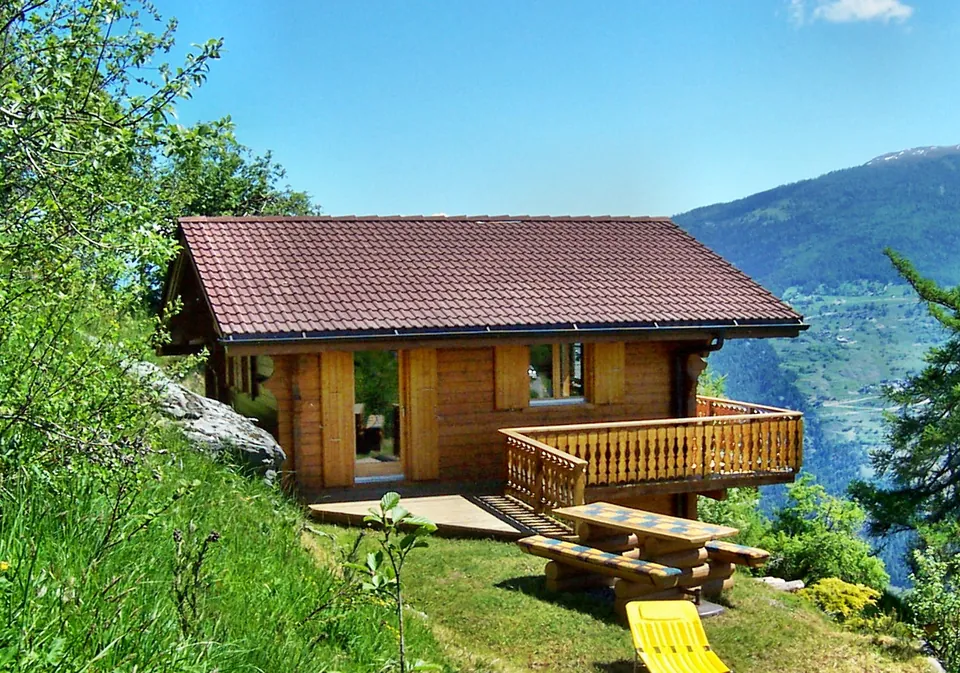 Chalet im Sommer mit Terrasse und Gartenmöbeln
